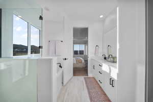Full bathroom featuring double vanity, connected bathroom, a shower stall, a garden tub, and recessed lighting