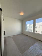 Unfurnished room featuring a barn door, a textured ceiling, and carpet floors