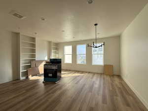 Unfurnished living room with wood finished floors, a textured ceiling, and a chandelier