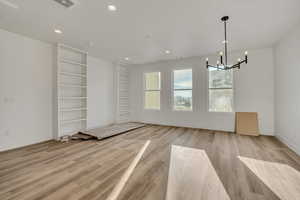Unfurnished dining area featuring light wood-style flooring and suspended lighting