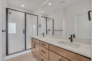 Bathroom featuring a shower stall, double vanity, and recessed lighting
