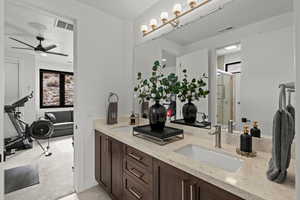 Full bathroom with double vanity, a shower stall, light colored carpet, and a ceiling fan
