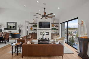 Living room with a ceiling fan, light wood-style flooring, a fireplace, vaulted ceiling, and recessed lighting