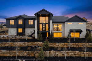 View of front of property with a balcony, a shingled roof, and stone siding