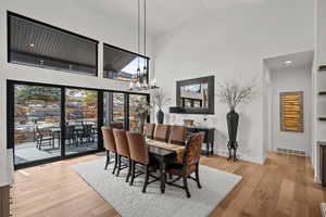 Dining area featuring light wood finished floors, a chandelier, and a high ceiling