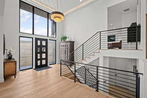 Entrance foyer with a high ceiling, light wood-type flooring, and suspended lighting