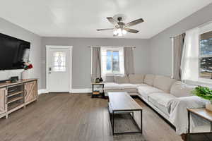 Living area with a ceiling fan and dark wood-style floors