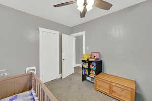 Bedroom with light colored carpet, a ceiling fan, and a closet