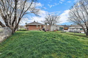 Rear view of house featuring brick siding, a fenced backyard, and a chimney