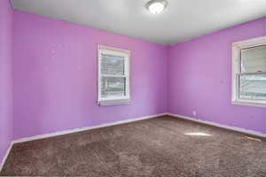 Spare room with dark colored carpet and baseboards
