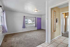 Foyer with light carpet, a textured ceiling, and light tile patterned floors