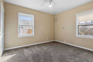Unfurnished room featuring ceiling fan and dark colored carpet