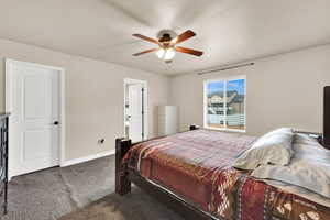 Bedroom with dark carpet, a ceiling fan, a textured ceiling, and ensuite bathroom