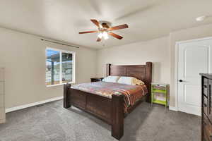 Bedroom with dark carpet, a ceiling fan, and a textured ceiling