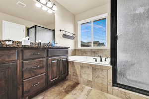 Full bathroom with vanity, a bath, and a stall shower