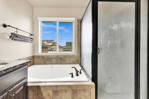 Bathroom featuring vanity, a garden tub, and a shower stall