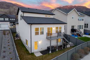 Back of house at dusk with a fenced backyard, a patio area, stucco siding, a shingled roof, and a deck with mountain view