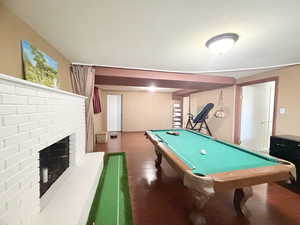 Recreation room featuring a brick fireplace, billiards, and dark wood finished floors