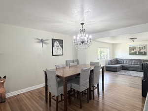 Dining room featuring wood finished floors, a textured ceiling, and a chandelier