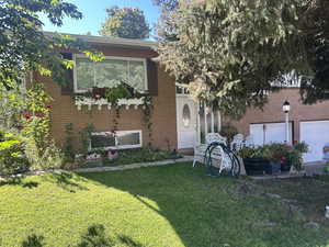 View of front of house with a front yard, brick siding, and a garage