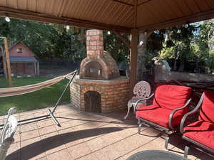 View of patio / terrace with an outdoor brick fireplace and an outbuilding