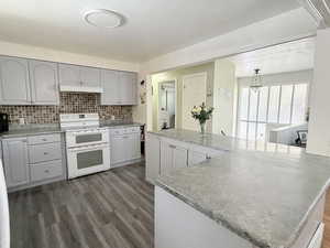 Kitchen featuring double oven range, gray cabinetry, dark wood finished floors, and decorative backsplash