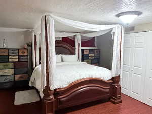 Bedroom featuring a textured ceiling, a closet, and dark wood finished floors
