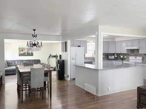 Dining space with a textured ceiling, dark wood finished floors, and suspended lighting