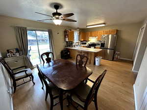 Dining space featuring light wood-style floors, a textured ceiling, and ceiling fan