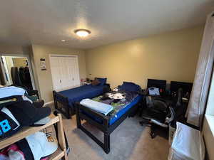 Bedroom with carpet flooring, a closet, a textured ceiling, and an office area
