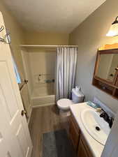 Bathroom featuring vanity, dark wood-style flooring, shower / tub combo, and a textured ceiling