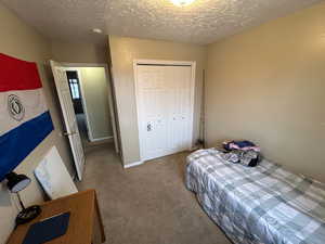 Bedroom featuring carpet floors, a closet, and a textured ceiling