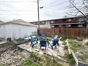 Fenced backyard with a fire pit, a patio, and an outbuilding