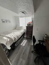 Bedroom featuring a textured ceiling and dark wood-style flooring