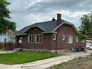 View of side of home featuring brick siding, a yard, a chimney, and a shingled roof