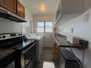 Laundry area with a textured ceiling, dark wood-style floors, and washing machine and clothes dryer