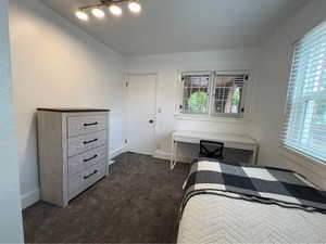 Bedroom featuring dark colored carpet and baseboards
