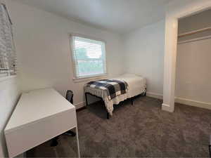 Bedroom with dark carpet and baseboards