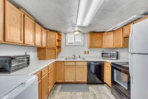 Kitchen with open shelves, black appliances, light countertops, and washer / dryer