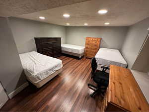 Bedroom featuring a textured ceiling, dark wood finished floors, and recessed lighting