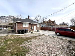 Rear view of house featuring brick siding, a shingled roof, and a chimney