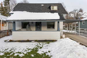 View of front facade featuring covered porch, roof with shingles, an attached carport, and concrete driveway