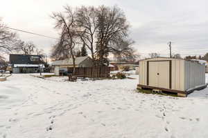 Yard layered in snow with a storage unit