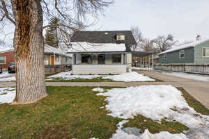 View of front of home with covered porch, concrete driveway, an attached carport, and a shingled roof