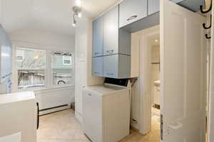 Laundry room with washer / clothes dryer, a baseboard radiator, light tile patterned flooring, and lofted ceiling