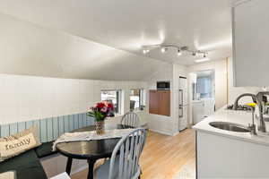 Kitchen with tile walls, light stone countertops, light wood-type flooring, freestanding refrigerator, and built in microwave