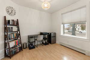 Office area with a baseboard heating unit and light wood finished floors