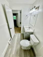 Half bathroom featuring light wood-style floors, vanity, and a baseboard radiator