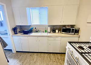 Kitchen featuring light countertops, white gas range, and white cabinetry