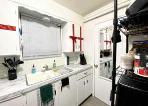 Kitchen featuring light countertops, white cabinets, tasteful backsplash, and concrete floors